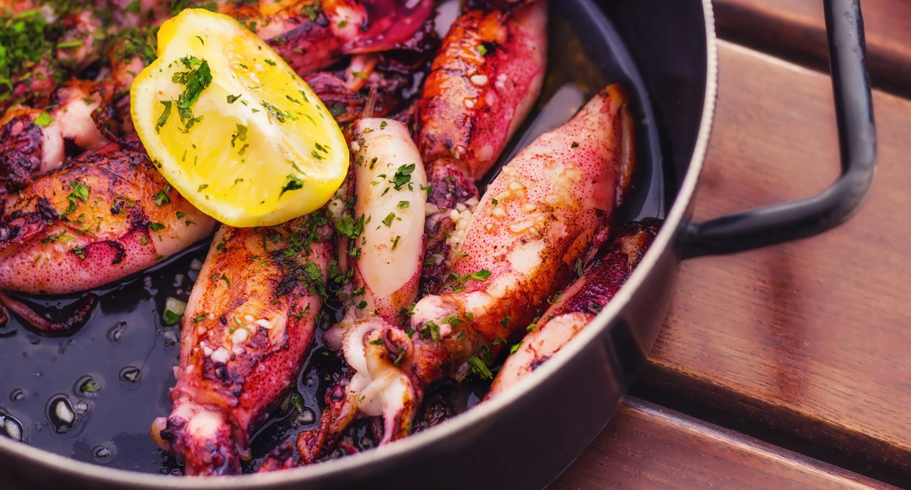 Grilled squid with lemon and parsley in a pan, a classic Dalmatian seafood dish served in Split