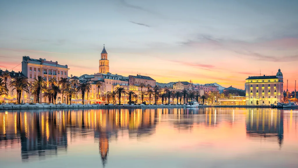 The Riva waterfront and the bell tower of Split cathedral reflected in still water at sunrise