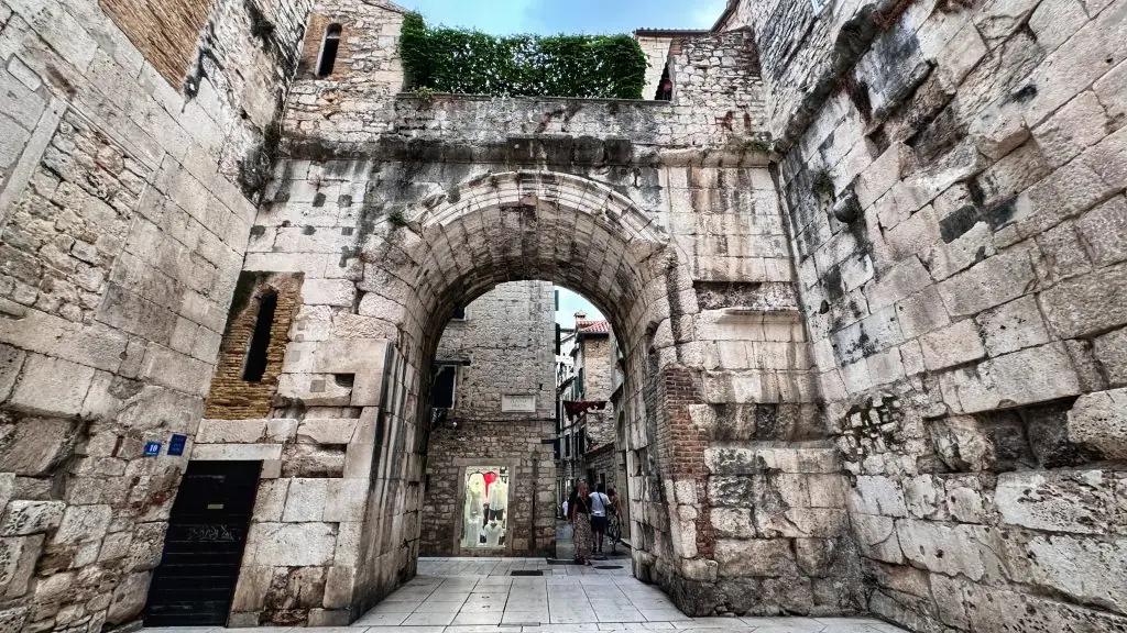 The Roman arch of one of Diocletian's Palace gates in Split, framed by weathered limestone walls under a soft grey sky