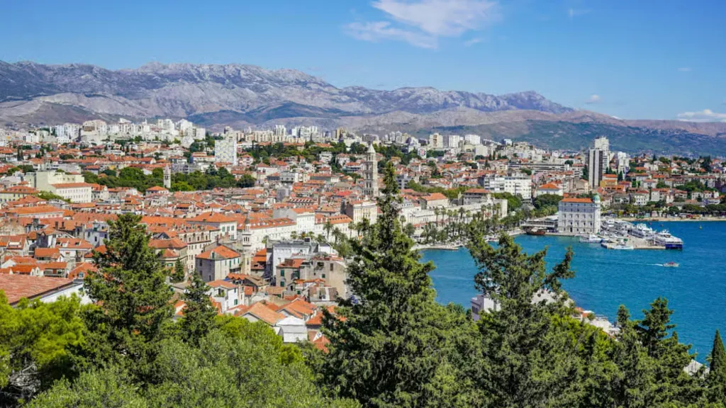 Split's old town and harbour seen from the green pine slopes of Marjan on a clear spring day, with the mountains behind