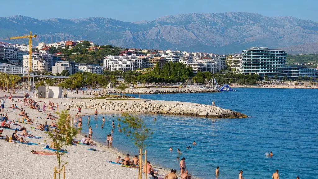 Swimmers in clear water below pine trees at a beach in Split on a bright summer morning