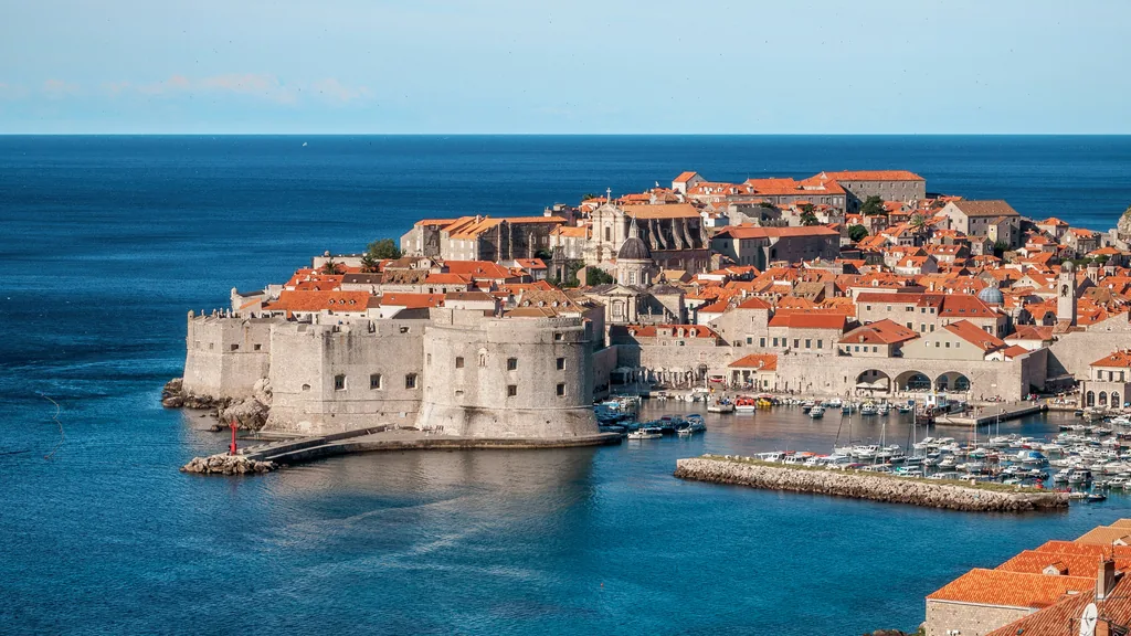 Dubrovnik's walled old town and old harbour seen from above, with the city walls and terracotta roofs above deep blue sea