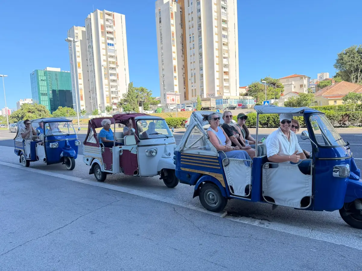 A convoy of three retro tuk tuks driving through Split on a sunny day