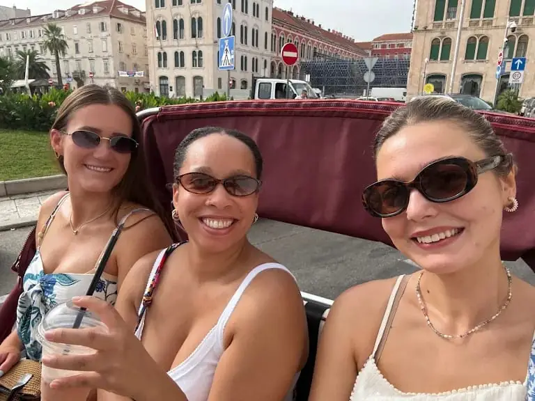 Three friends smiling with cold drinks aboard a tuk tuk in Split
