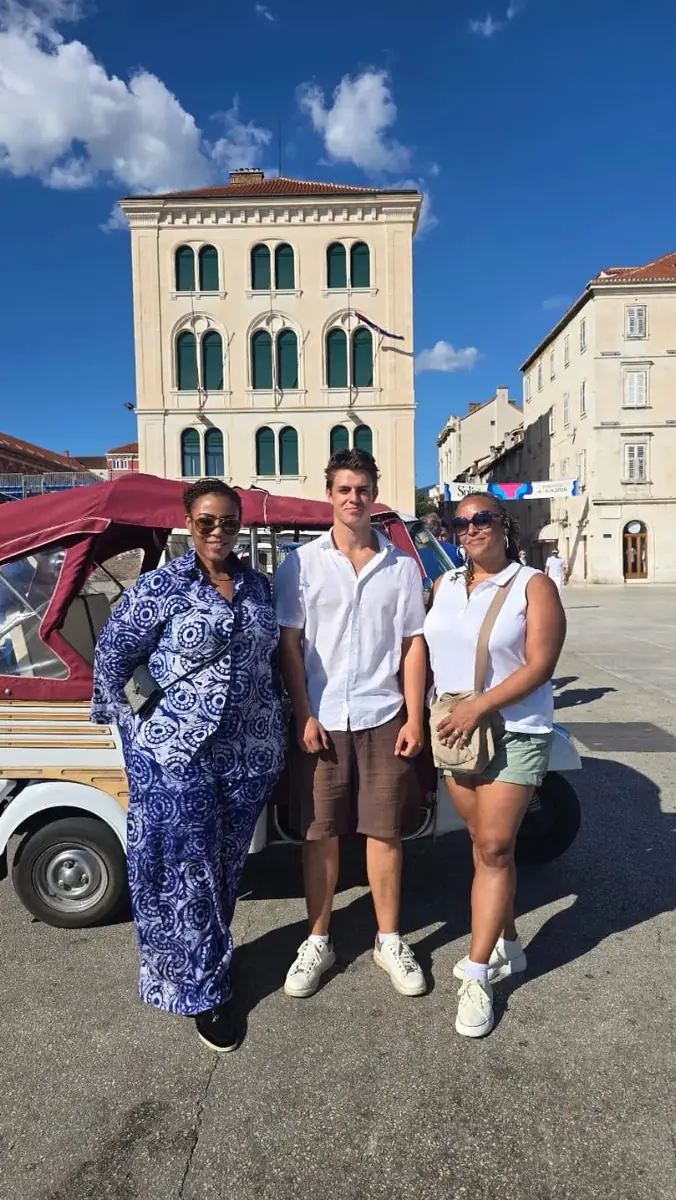 Guests standing beside their tuk tuk on a sunny square in Split