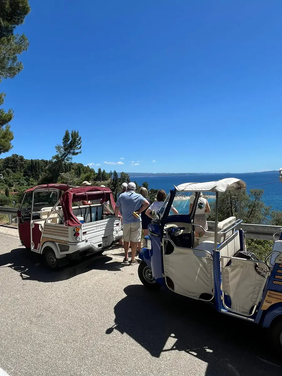 Two tuk tuks stopped at a sunny coastal viewpoint above the Adriatic